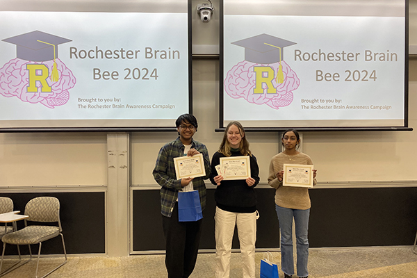 The winner and runners up smiling at the camera while holding their certificates.